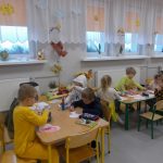 Dzieci siedzące przy dwóch stolikach tworzą prace plastyczne.