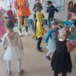 Dzieci w strojach karnawałowych tańczą w takt muzyki.