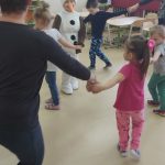 Dzieci wraz z nauczycielką i bałwankiem tańczą w kółeczku