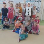 Grupa piętnastu dzieci wraz z Bałwankiem pozuje do fotografii.