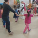 Dzieci wraz z nauczycielką i bałwankiem tańczą w kółeczku