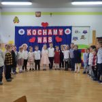 Dzieci ustawione w półkolu ś[iewają piosenkę
