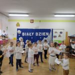 Duża grupa dzieci wykonuje ćwiczenia z kartkami papieru.