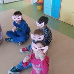 Czworo dzieci siedzi na podłodze i patrzy przez różowe okulary